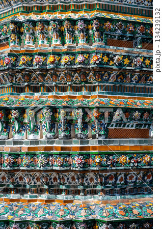 Detailed view of the ornate towers of Wat Arun in Bangkok, Thailand, showcasing rich ceramic floral patterns, sculpted figures, and intricate decorations under bright daylight. Detailed view of the ornate towers of Wat Arun in Bangkok, Thailand, showcasing rich ceramic floral patterns, sculpted figures, and intricate decorations under bright daylight. 134239132