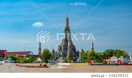 View of Wat Arun across the Chao Phraya River in Bangkok, Thailand, captured on a bright sunny day with the temple iconic spires rising above the shimmering water. View of Wat Arun across the Chao Phraya River in Bangkok, Thailand, captured on a bright sunny day with the temple iconic spires rising above the shimmering water. 134239151