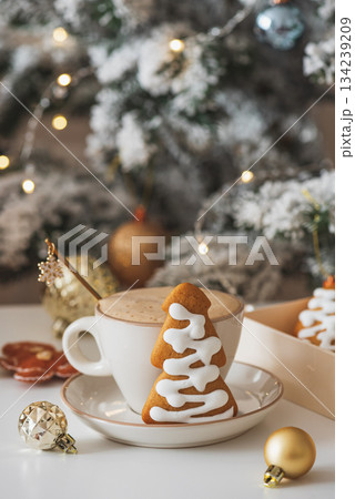 Cup of Hot Coffee with Christmas Gingerbread tree-shaped Cookies and Ornaments in Festive Setting Cup of Hot Coffee with Christmas Gingerbread tree-shaped Cookies and Ornaments in Festive Setting 134239209
