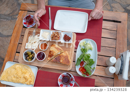 Traditional Turkish breakfast spread with fresh bread, olives, cheese, tomatoes, cucumbers, and variety of jams and spreads. Enjoyed in vibrant setting, capturing essence of Turkish morning culture. 134239328