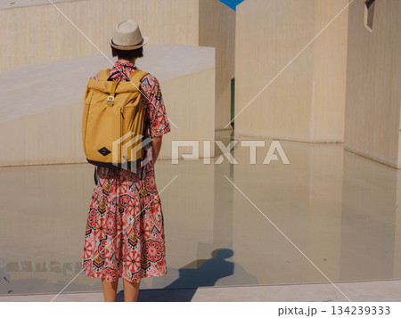 Young woman exploring Qasr Al Hosn Park in Abu Dhabi. Surrounded by lush greenery and historical landmarks, she enjoys the serene atmosphere and Emirati heritage in heart of city. 134239333