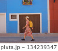 Woman in dress strolls through colorful streets of Spanish coastal town of La Vila Joiosa or Villajoyosa. sunny winter atmosphere highlights charm of Mediterranean architecture and quiet seaside life 134239347
