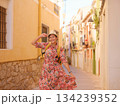 Woman in dress strolls through colorful streets of Spanish coastal town of La Vila Joiosa or Villajoyosa. sunny winter atmosphere highlights charm of Mediterranean architecture and quiet seaside life 134239352