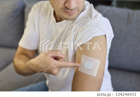Man pointing to diabetes patch sensor on upper arm for continuous glucose care. Man pointing to diabetes patch sensor on upper arm for continuous glucose care. 134240431
