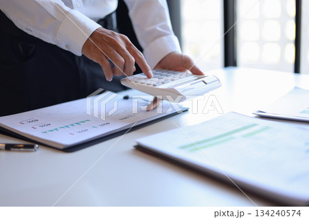 Businessman working in office using calculator. Businessman working in office using calculator. 134240574