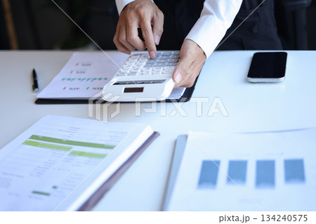 Businessman working in office using calculator. Businessman working in office using calculator. 134240575