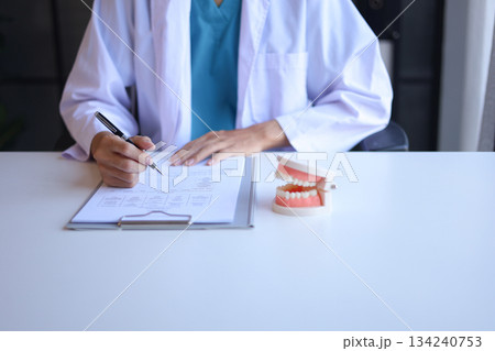 Dentist working in office writing diagnose oral health issues. Dentist working in office writing diagnose oral health issues. 134240753