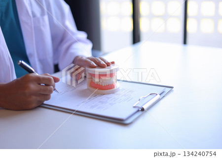 Dentist working in office writing diagnose oral health issues. Dentist working in office writing diagnose oral health issues. 134240754