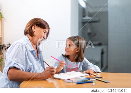 Smiling grandmother and granddaughter drawing 134241054
