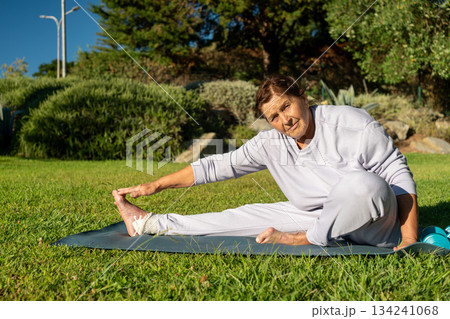 Determined elderly woman touching toes while 134241068