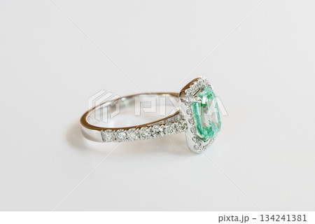 A green and white ring with diamonds and a halo 134241381