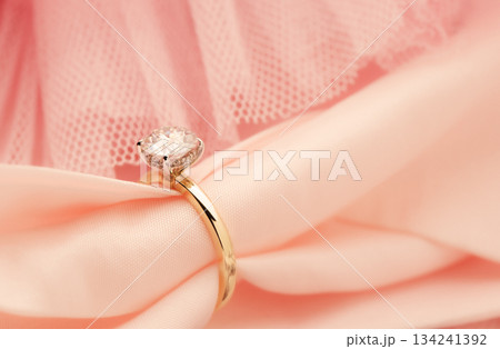 A gold and diamond ring is on a pink cloth A gold and diamond ring is on a pink cloth 134241392