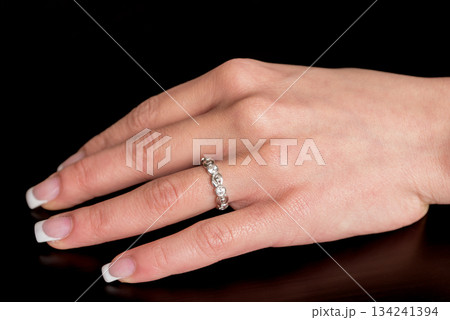 A woman's hand holding a ring with diamonds on it 134241394