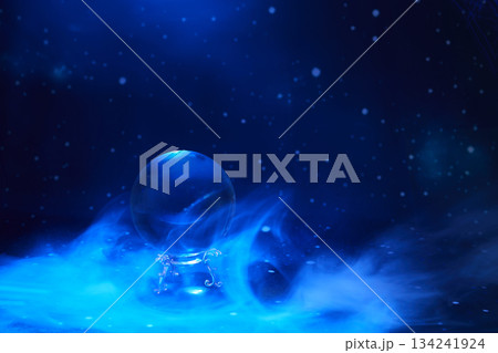 Mystical Crystal Ball. A crystal ball amidst swirling blue mist and a starry background. 134241924