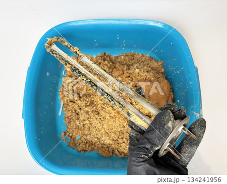 Plumber hand holding a boiler heating element covered with limescale, hard water residue, boiler maintenance and cleaning, scale removal, water heater repair 134241956