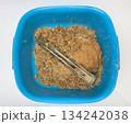 Boiler heating element covered with hard water limescale lying in a bowl with residue after boiler cleaning, damaged heater element, scale buildup concept 134242038