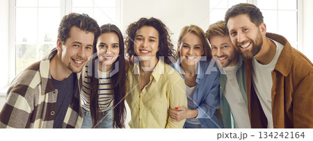 Smiling happy young people friends standing together and looking cheerful at the camera. 134242164