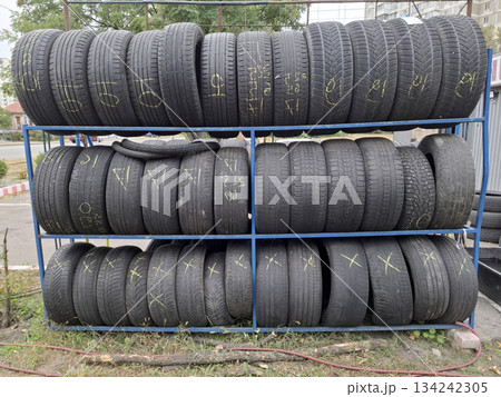 Old black car tires are stacked near a tire shop Old black car tires are stacked near a tire shop 134242305