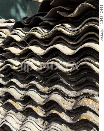 Natural patterns of worn roofing tiles stacked in the afternoon sun 134242441