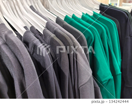 Colorful t-shirts hang on display in a retail store during a sunny afternoon 134242444