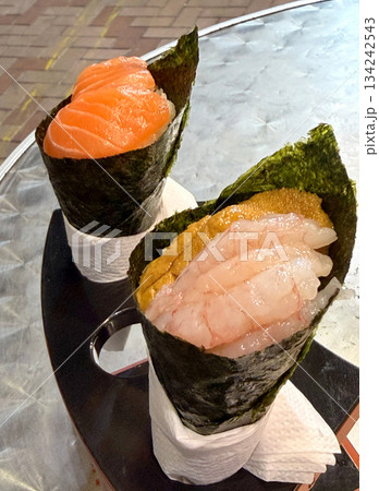 Two delicious temaki sushi cones, one with salmon and the other with shrimp and uni 134242543