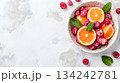 Top view of fresh citrus and berries in a bowl on white background with empty space. Vibrant summer food theme 134242781