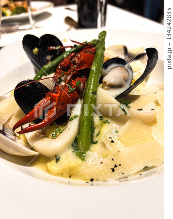Gourmet seafood pasta creating a luxurious dining experience, combining lobster, mussels, squid, and clams with tender asparagus and parmesan in a rich creamy sauce 134242835