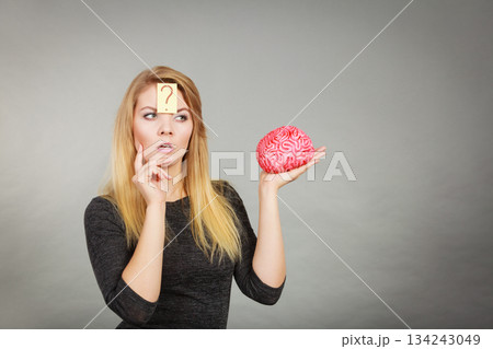 Woman thinking and holding fake brain 134243049