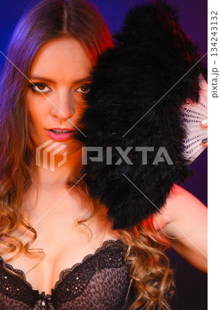 Woman holding carnival feather fan in hand. 134243132