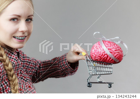 Woman holding shopping cart with brain Woman holding shopping cart with brain 134243244