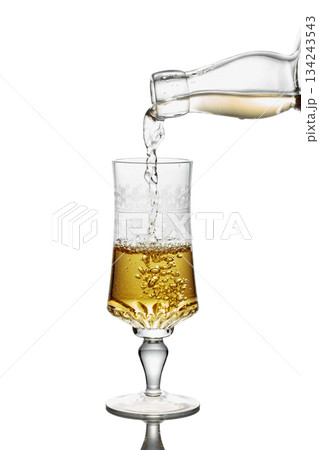 Gold liquor pouring into a glass on a white background. Gold liquor pouring into a glass on a white background. 134243543