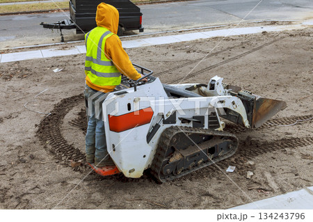 Construction worker operates small track loader on construction site in residential area Construction worker operates small track loader on construction site in residential area 134243796