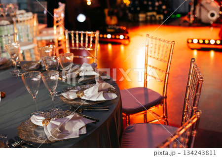 Elegantly set banquet table with gold chargers and ambient stage lighting 134243811