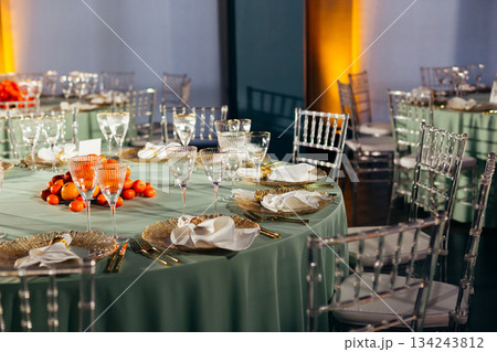 Wide shot of banquet hall with multiple tables, Chiavari chairs, and citrus centerpiece Wide shot of banquet hall with multiple tables, Chiavari chairs, and citrus centerpiece 134243812
