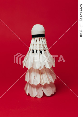 White feather shuttlecock on red background, evoking a minimalist Christmas tree 134243829