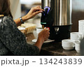 Woman pouring coffee from a thermal dispenser into a cup 134243839