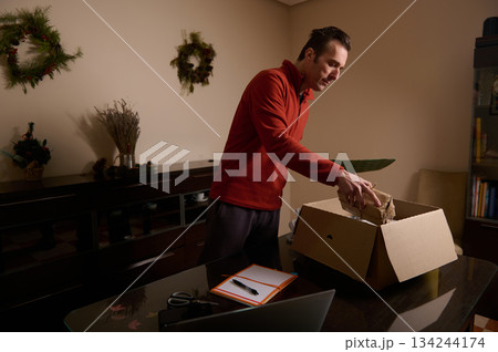 Man Packing Box At Home During Christmas Season, Preparing Gift And Move Man Packing Box At Home During Christmas Season, Preparing Gift And Move 134244174