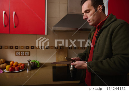 Man Preparing Food in Modern Kitchen, Slicing with Knife Near Fresh Fruits 134244181