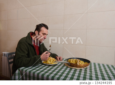 Man Eating Fries at Home Kitchen With Checkered Tablecloth, Simple Cozy Dinner Scene 134244195