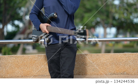 Bass Guitarist Against Light Brown Wall Outdoor Night Ambition, Building Future Trust, Dark Body Background 134244536