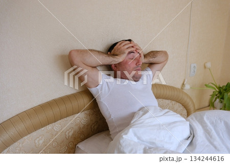A man holds his head and yawns in bed Man with blanket cover his head feel sleepy and yawn close the eye on white isolated background 134244616