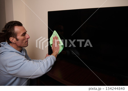 Man Cleaning Television Screen With Soft Cloth In Living Room For Sparkling Surface Man Cleaning Television Screen With Soft Cloth In Living Room For Sparkling Surface 134244840