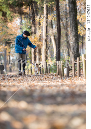 秋の公園で犬と散歩を楽しむ男性の笑顔とペットとの時間の全身	 134247625