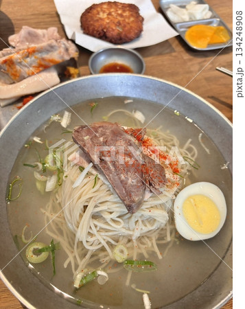 Authentic Pyongyang naengmyeon with chewy buckwheat noodles in cold, clear broth, offering a refreshing and delicate flavor. Perfect for traditional Korean cuisine menus and summer dishes. Authentic Pyongyang naengmyeon with chewy buckwheat noodles in cold, clear broth, offering a refreshing and delicate flavor. Perfect for traditional Korean cuisine menus and summer dishes. 134248908