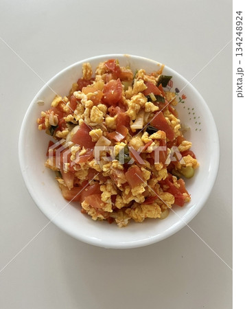 A simple dish of scrambled eggs with juicy tomatoes, seasoned lightly for a balance of flavor. Perfect as a quick and nutritious meal option. 134248924