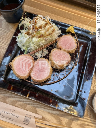 Crispy tonkatsu, a Japanese-style breaded and deep-fried pork cutlet, served with shredded cabbage and drizzled with savory sauce. A delightful balance of crunchy texture and juicy meat. 134248931
