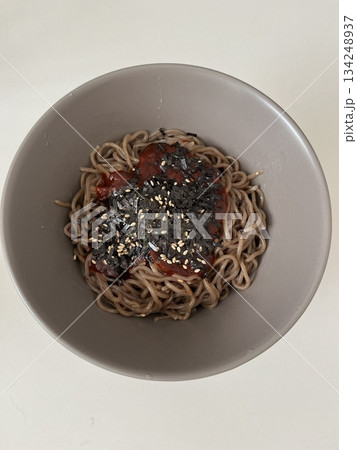 Deulgireum makguksu with buckwheat noodles coated in fragrant perilla oil, topped with fresh vegetables and sesame seeds, showcasing glossy texture, earthy colors, and simple rustic in detail 134248937
