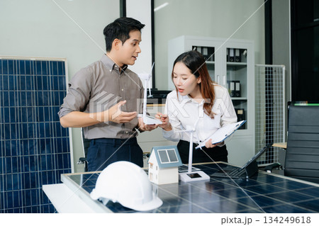 Engineers discuss solar panels and turbines in office, working on clean energy design, sustainable power Engineers discuss solar panels and turbines in office, working on clean energy design, sustainable power 134249618