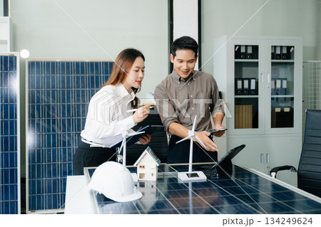Engineers discuss solar panels and turbines in office, working on clean energy design, sustainable power 134249624