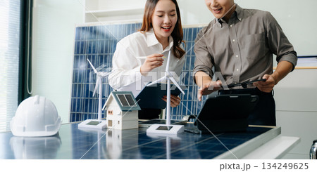 Engineers discuss solar panels and turbines in office, working on clean energy design, sustainable power 134249625